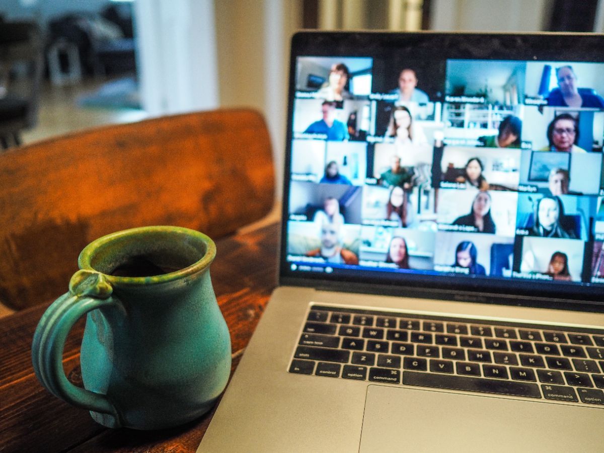 Computer showing a Zoom call with multiple people and a mug beside the computer