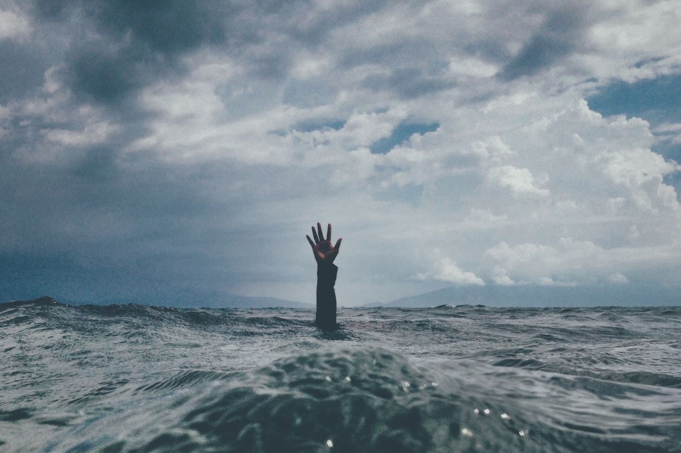 Arm reaching out of the ocean up to the sky