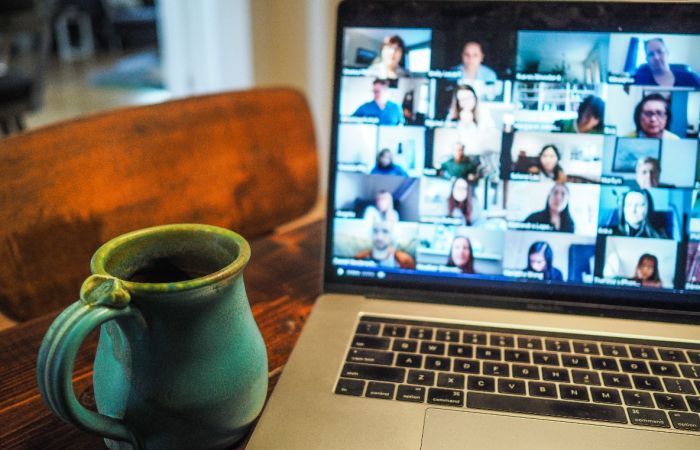 Computer showing a Zoom call with multiple people and a mug beside the computer