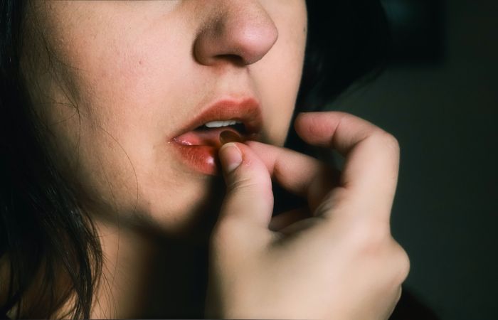 Woman placing a tablet in her mouth 